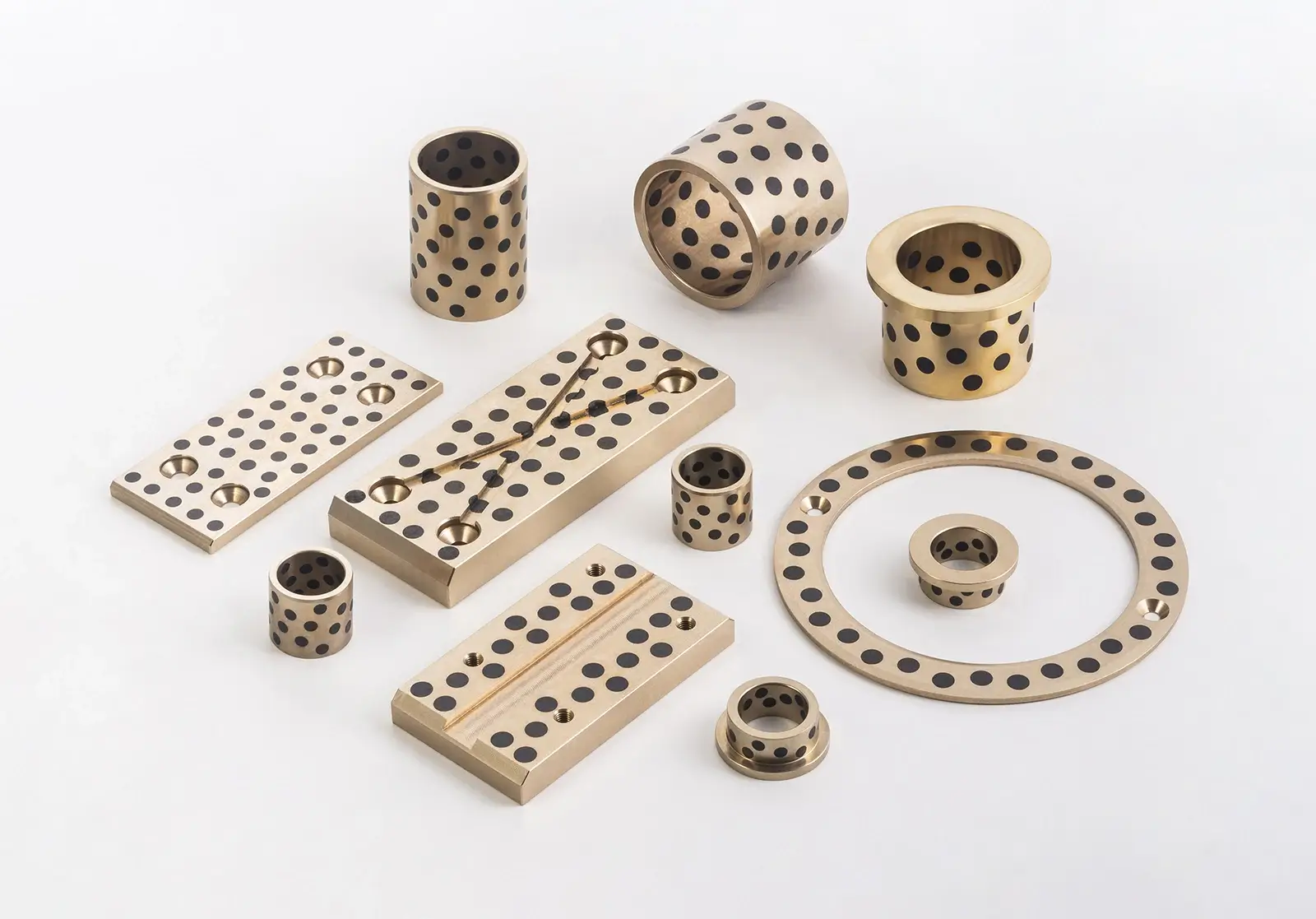 Yellow brass bushing with black graphite plugs arranged in a geometric pattern
